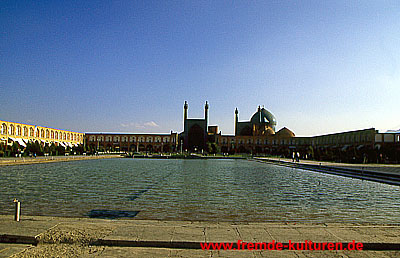Isfahan -  Meydan-e Imam. Dieser 150 m breite und gut 500 m lange, exakt rechteckige Platz gehörte zum Palastareal, das in der Regierungszeit Shah Abbas 1. konzipiert und errichtet wurde. Doppelstöckige Arkaden, in denen zu ebener Erde Läden untergebracht sind, rahmen den gesamten Platz. An den Schmalseiten werden die Arkaden von hohen, reich verzierten Iwanen unterbrochen, die im Norden in den kaiserlichen Bazar führen, im Süden in die Imam-Moschee. An den Längsseiten des Platzes öffnen sich die Arkaden im Osten für die Shaikh Lotfollah-Moschee, im Westen zum Torpalast Ali Qapu. Alle Gebäude rund um den Imam-Platz gehörten zum Gesamtkonzept der Königspaläste in safawidischer Zeit. Es wird berichtet, daß Shah Abbas auf diesem Platz auch Polo-Spiele und Millitärparaden veranstalten ließ, denen er von der Terrasse des Ali Qapu aus zuschaute. Quelle: M. Rashad: Iran. 279 f. Ostfildern 2006.